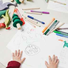 kid on white table using a drawing and coloring book